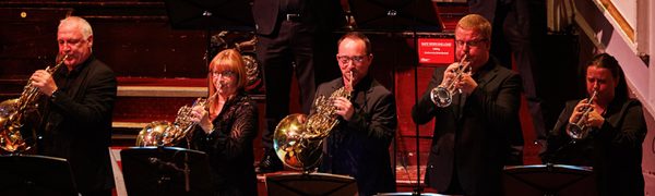 a group of brass musicians stand on stage