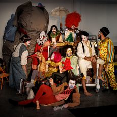 A group of people wearing clown costumes surrounded by circus props