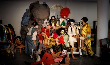 A group of people wearing clown costumes surrounded by circus props