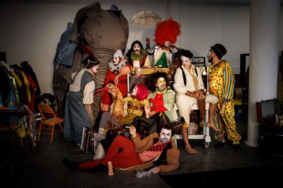 A group of people wearing clown costumes surrounded by circus props