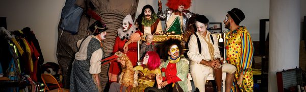 A group of people wearing clown costumes surrounded by circus props