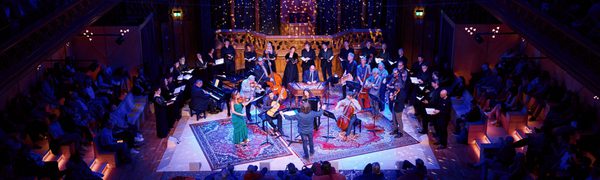 An ensemble of musicians performing on stage at The Hub surrounded by an audience