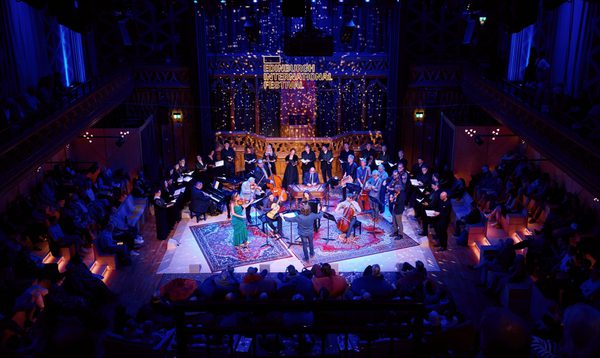 An ensemble of musicians performing on stage at The Hub surrounded by an audience