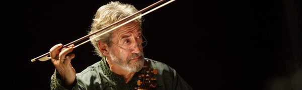 A man plays a viol, looking off to the right with his bow in the air