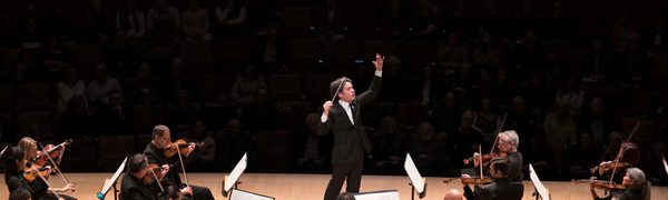 A conductor on stage facing the orchestra