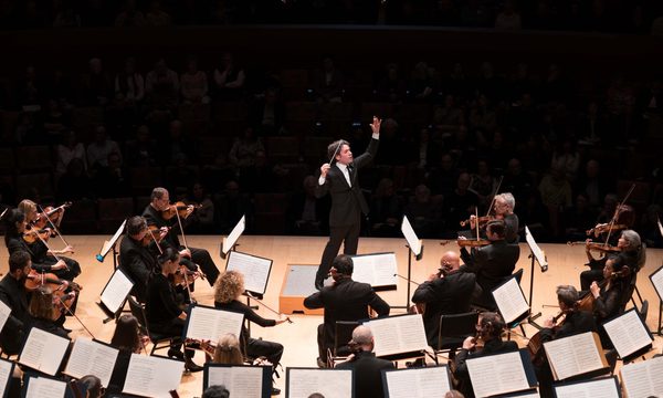 A conductor on stage facing the orchestra