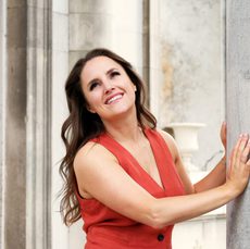 a women in a red waistcoat smiles into the distance