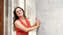 a women in a red waistcoat smiles into the distance