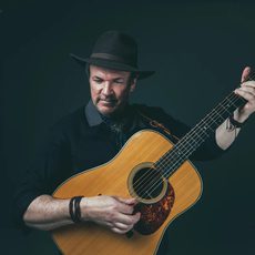 A man stands playing an acoustic guitar