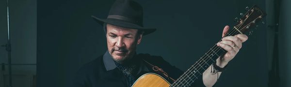 A man stands playing an acoustic guitar