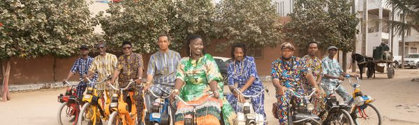 a group of people in colourful clothes sit on bikes smiling