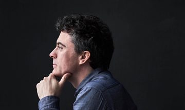 Side profile of a man with his chin resting in his hand looking off into the distance