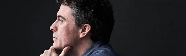 Side profile of a man with his chin resting in his hand looking off into the distance