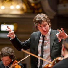 A close up of a conductor conducting his orchestra