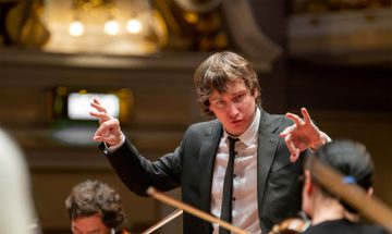A close up of a conductor conducting his orchestra