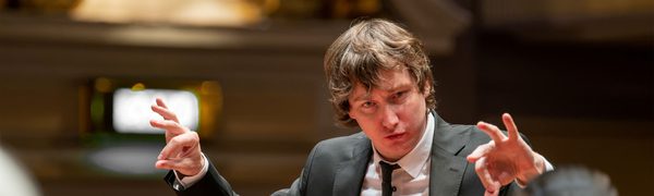 A close up of a conductor conducting his orchestra