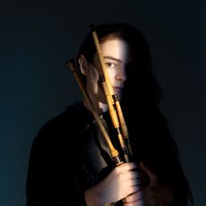 A woman mostly obscured by shadow holding a bagpipe instrument