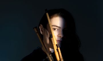 A woman mostly obscured by shadow holding a bagpipe instrument