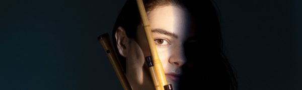 A woman mostly obscured by shadow holding a bagpipe instrument
