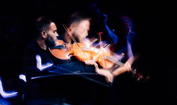 a man plays the viola d’amore in a dark room
