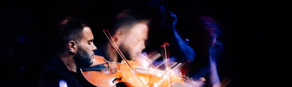 a man plays the viola d’amore in a dark room