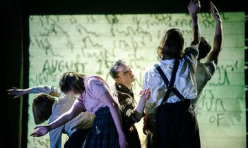 Five performers grouped together on stage, each with an arm raised and poised at different angles