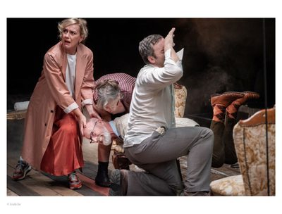 A man crouched on the floor while surrounded by three other people looking distressed