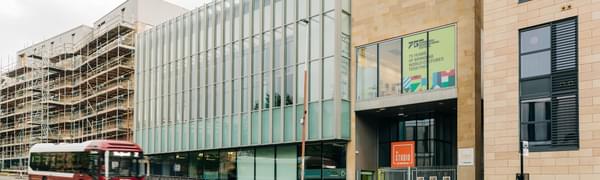 Facade of The Studio, with a car and bus blurrily in motion in front.