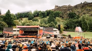 Photo of the audience and stage in Princess Street Gardens with Edinburgh Castle in the background