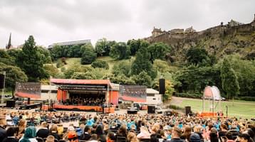 Photo of the audience and stage in Princess Street Gardens with Edinburgh Castle in the background