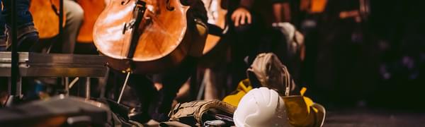 Cello on stage with hard hat and building materials in focus.