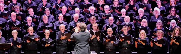 The Edinburgh Festival Chorus perform, standing five rows deep, with their conductor stood in front of them