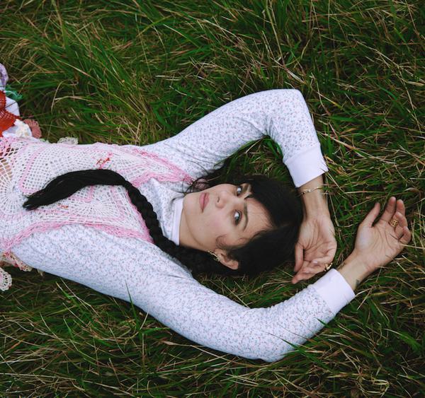 A women is lying on some grass looking up at the camera