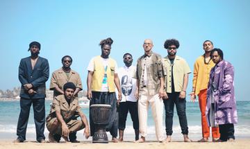 Men standing on beach behind drum facing camera