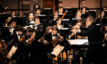 orchestra musicians playing instruments on stage with conductor