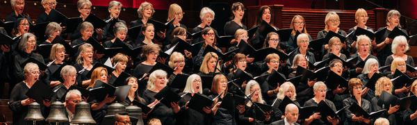 Large female choir singing above orchestra musicians
