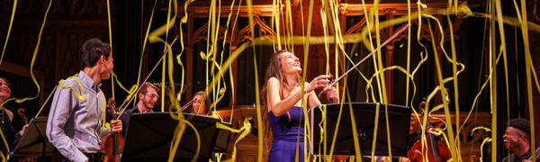 Yellow streamers descend from the ceiling on Nicola Benedetti and a group of musicians.