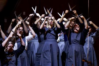 Group of women wearing blue dresses, holding scissors in the air above their heads