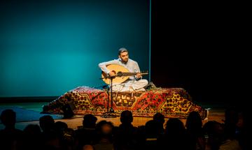 a man sits on a persian rug playing a stringed instrument