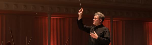 Man holding arms in air conducting orchestra