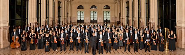 Symphony Orchestra standing together in grand hall holding their instruments