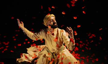 Man dancing among cascading red flower petals