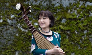 Woman looking off camera holding a stringed instrument