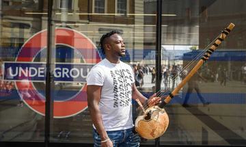 Man in street holding a string instrument