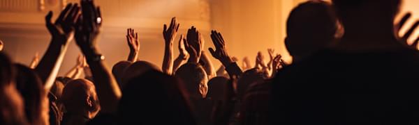 A crowd clap and raise their hands in the air during a gig.