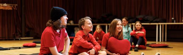 three children sit on the floor smiling
