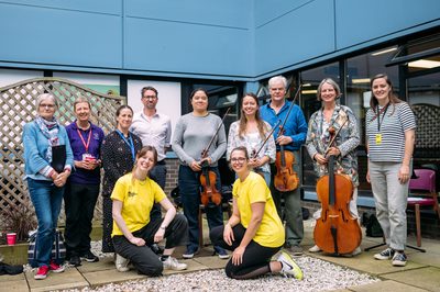 a group of musicians stand together smiling with two international festival staff in front of them