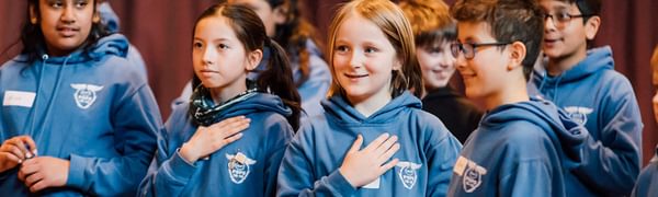 Children in blue hoodies smiling during a workshop