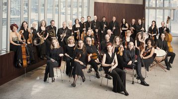 Photo orchestra stood and sat with instruments at a photo call