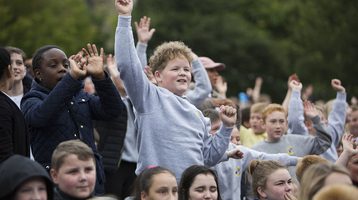 VMFC Schools Concert, School children dancing with hands up and smiling